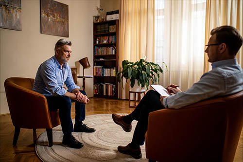 Мужчина сидит в кресле на сеансе психотерапии